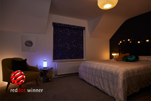 A children's bedroom warmly lit at night. The reddot winner logo is placed in the corner of the image.