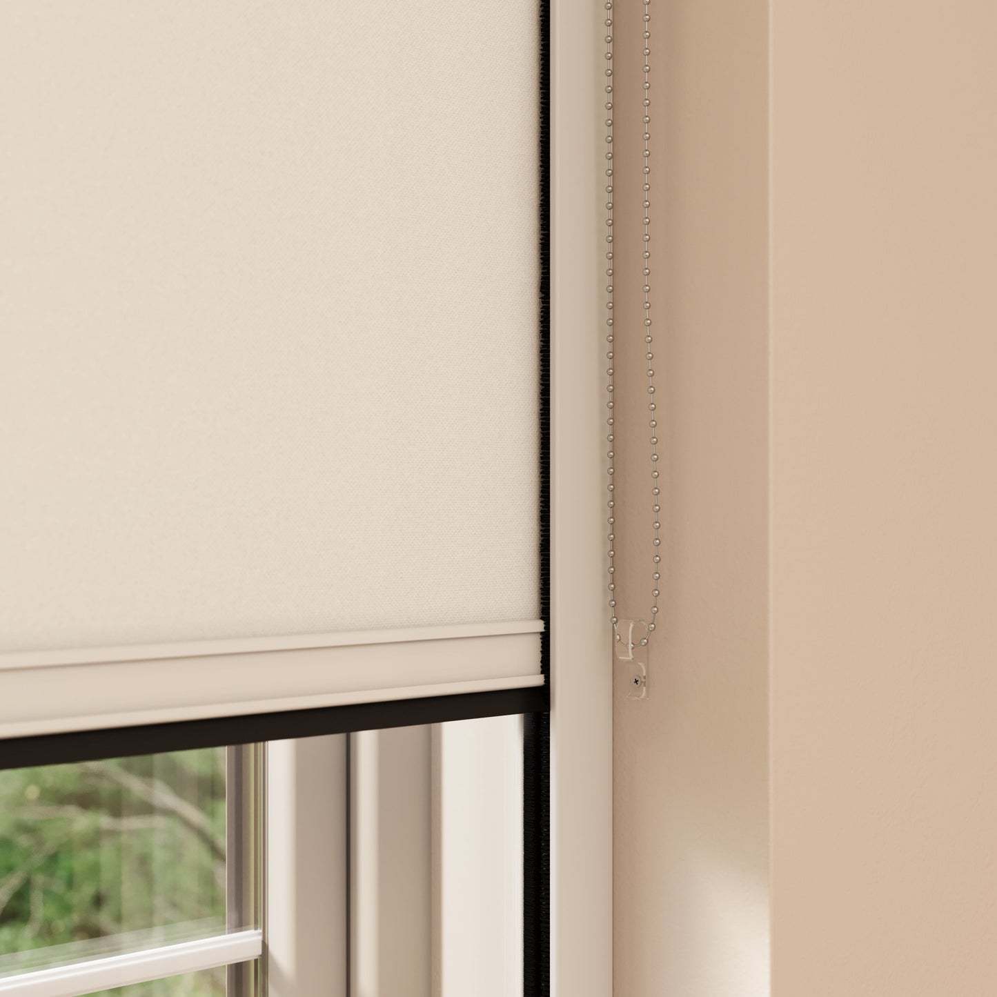 A close-up view of a window with a beige BlocOut blind partially drawn down. The shade is mounted inside the window frame, and there is a metal bead chain hanging on the right side, used to adjust the height of the shade. The wall around the window is painted in a light beige colour.